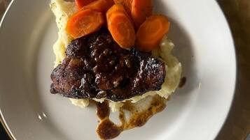 Un plato con carne, puré de papas y zanahorias en rodajas.