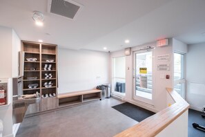 Un vestíbulo limpio y moderno con una recepción, un banco y una zona de almacenamiento con toallas dobladas ordenadamente.