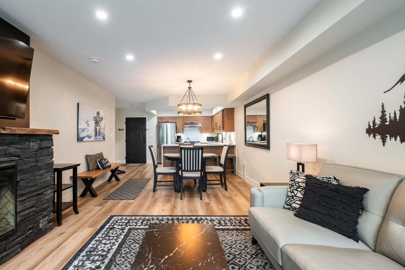 A modern living room with a fireplace, a dining area, and a kitchen.