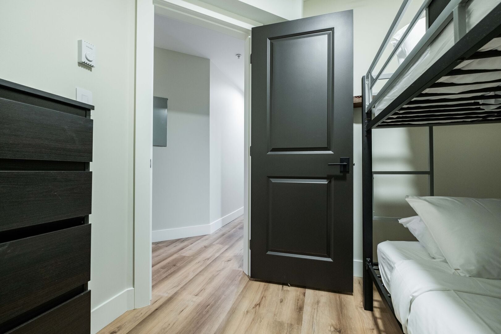 A room with a bunk bed, a closed door, and a wooden floor.