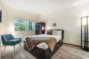 A bedroom with a bed, a chair, a wardrobe, and a window with a view of greenery. - Pet friendly | BBQ | Private balcony | Cable TV (Whistler)