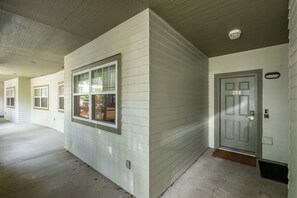 A corridor with white siding walls, a grey door marked with the number 204, and a window with a view of the outdoors. - Pet friendly | BBQ | Private balcony | Cable TV (Whistler)