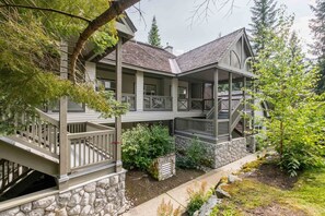 A two-story house with a stone foundation, a covered porch, and a staircase leading to the upper level. - Pet friendly | BBQ | Private balcony | Cable TV (Whistler)