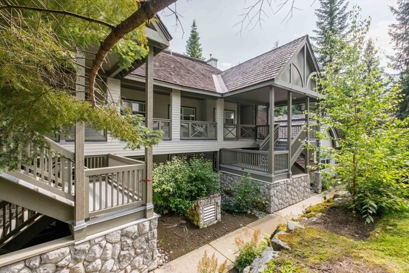 A two-story house with a stone foundation, a covered porch, and a staircase leading to the upper level.
