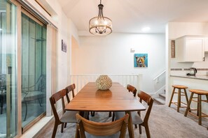 Een eethoek met een houten tafel, stoelen, een decoratieve vaas en een kroonluchter.