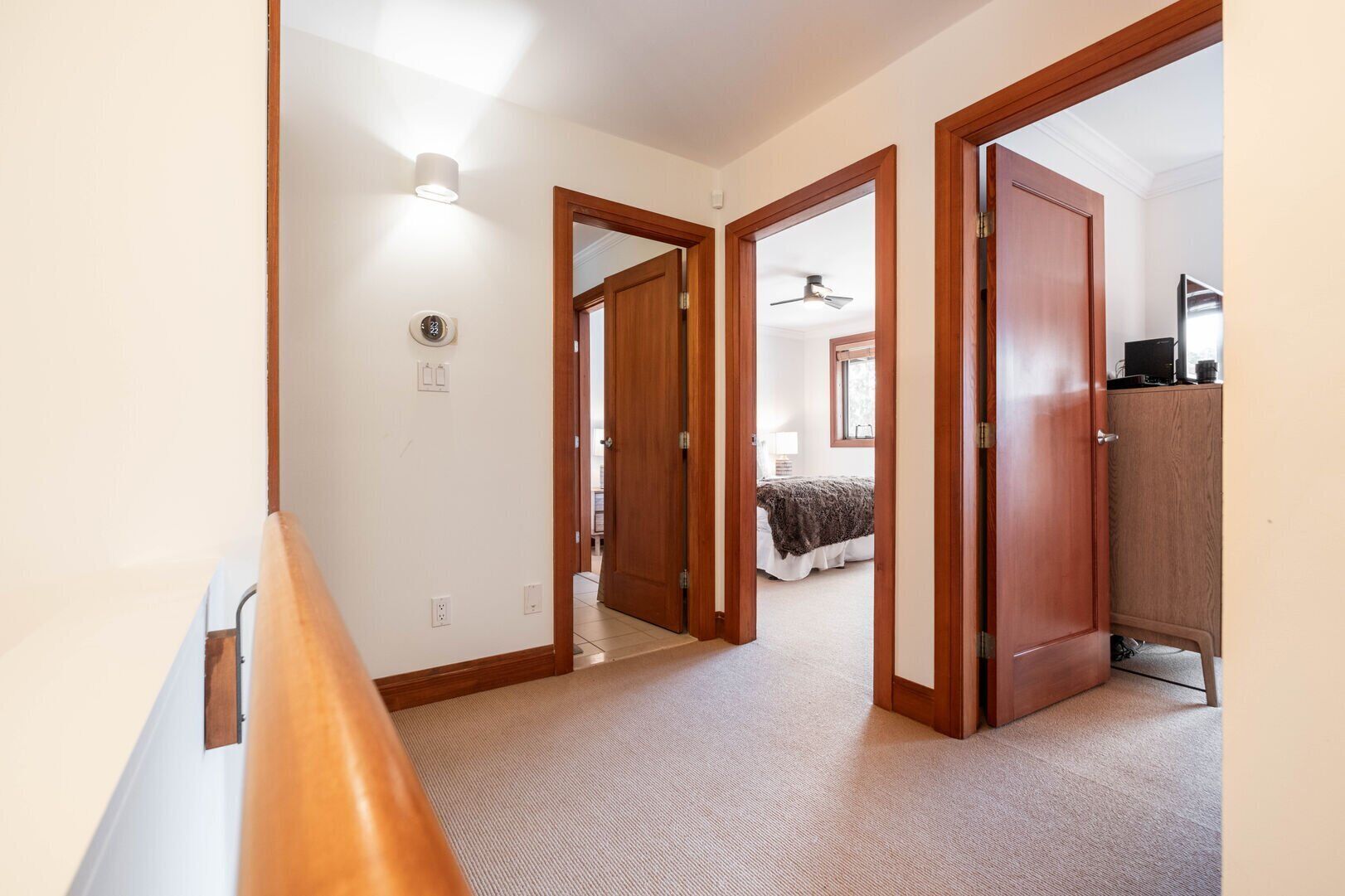 Un corridoio che porta a una camera da letto con un letto, un armadio e una ventola a soffitto.