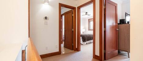 A hallway leading to a bedroom with a bed, a wardrobe, and a ceiling fan.