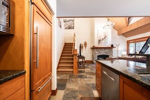 A kitchen with wooden cabinets, a stone fireplace, and a modern design. - Townhome | Private hot tub | BBQ | A/C | Pets (Whistler)