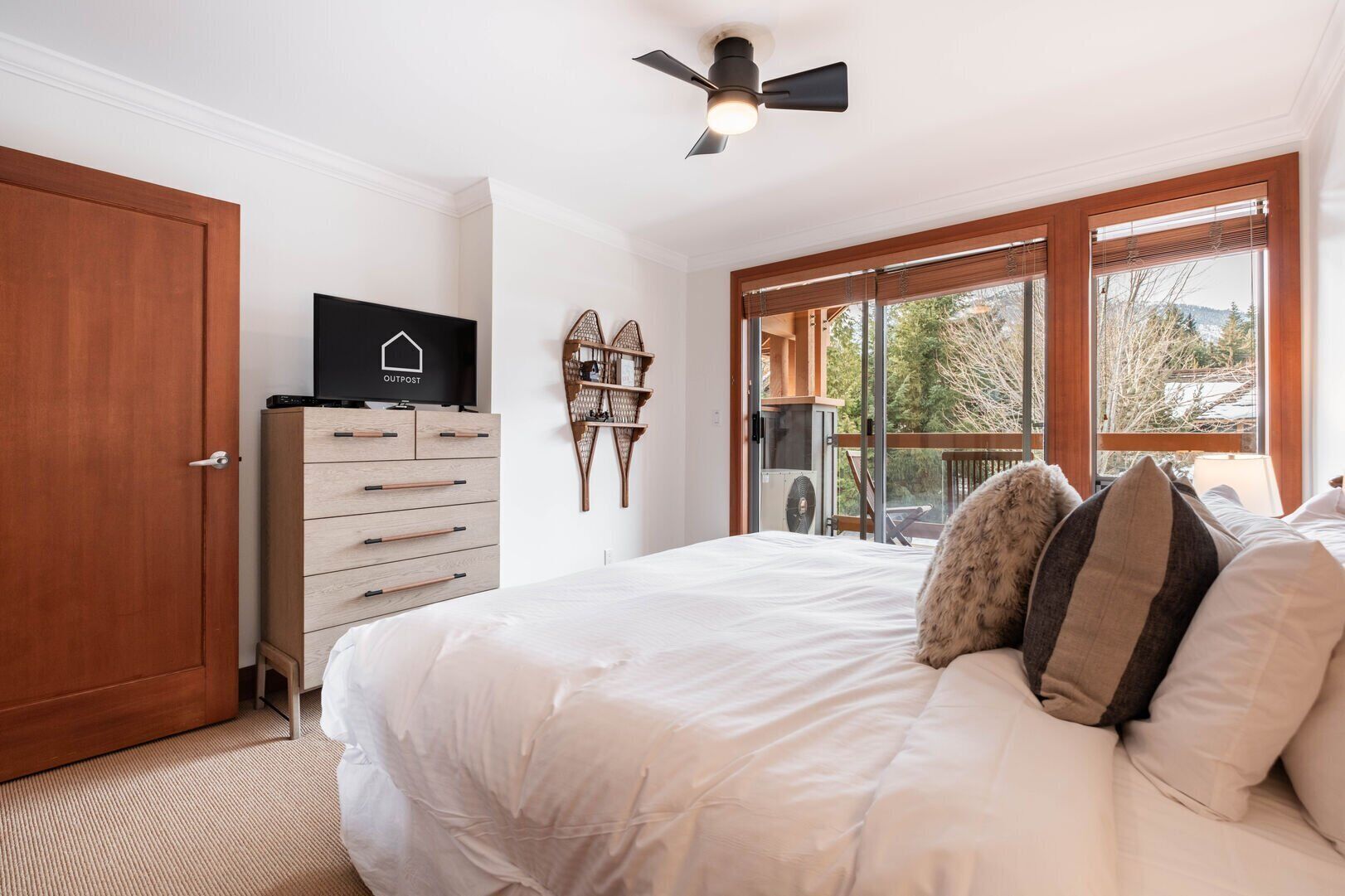 Ein Schlafzimmer mit einem großen Bett, einem Holzschrank, einem Deckenventilator und Blick ins Freie durch ein Fenster.