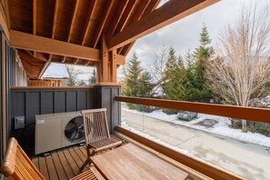 A wooden deck with a view of a snowy street and trees. - Townhome | Private hot tub | BBQ | A/C | Pets (Whistler)