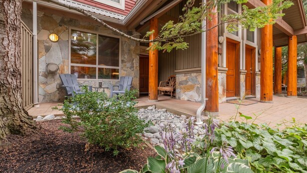 A stone exterior with a covered porch, outdoor seating, and a tree. - Great location | Complex hot tub | BBQ | Smart TVs (Whistler)
