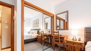 A hotel room with a bed, a desk, a chair, a nightstand, and a mirror. - Great location | Complex hot tub | BBQ | Smart TVs (Whistler)