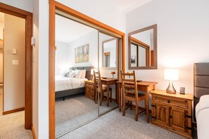 Ein Hotelzimmer mit einem Bett, einem Schreibtisch, einem Sessel, einem Nachttisch und einem Spiegel.