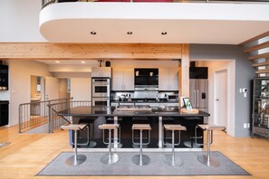 A modern kitchen with a central island, bar stools, stainless steel appliances, and a wooden ceiling. - Luxury Home | Private hot tub | Pets | BBQ | AC (Whistler)