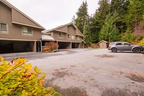A building with multiple garage doors and a parking area. - Townhome | Smart TVs | Pets | BBQ | Blueberry Hill (Whistler)