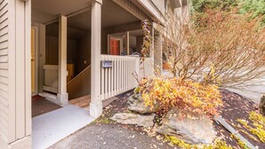 A two-story building with a covered porch, a stone pathway, and a small tree with autumn leaves. - Townhome | Smart TVs | Pets | BBQ | Blueberry Hill (Whistler)