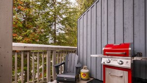 Ein Balkon mit Grill, einem Stuhl und einer Propangasflasche.
