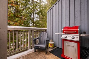 Ein Balkon mit Grill, einem Stuhl und einer Propangasflasche.