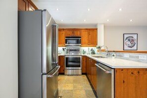 A modern kitchen with stainless steel appliances, wooden cabinets, and a granite countertop. - Townhome | BBQ | Pets | Free Parking | Wifi (Whistler)