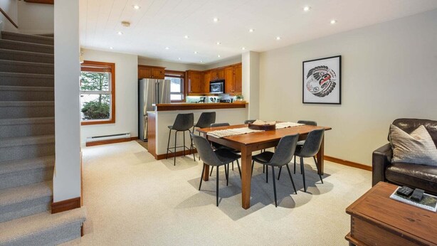 Eine moderne Küche mit Holzschränken, einem Edelstahlkühlschrank und einer Mikrowelle.