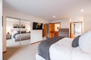 A bedroom with a bed, a TV, a wardrobe, and a mirror. - Townhome BBQ | Smart TV | Private Garage | Wifi (Whistler)
