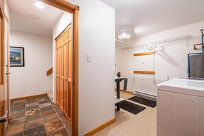 A hallway with a wooden wardrobe, a small table, a drying rack, and a washing machine. - Townhome BBQ | Smart TV | Private Garage | Wifi (Whistler)