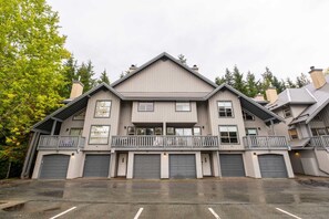 A multi-story building with a symmetrical facade, multiple garage doors, and a central balcony. - Townhome BBQ | Smart TV | Private Garage | Wifi (Whistler)