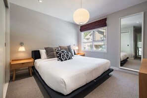 Ein Schlafzimmer mit einem großen Bett, zwei Nachttischen, einem Spiegel und einem Fenster mit Blick.
