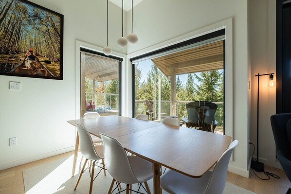 Ein modernes Interieur mit Essbereich, großen Fenstern und Blick ins Freie.