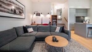 Ein modernes Wohnzimmer mit einer Eckcouch, einem Couchtisch und einer Küchenzeile im Hintergrund.