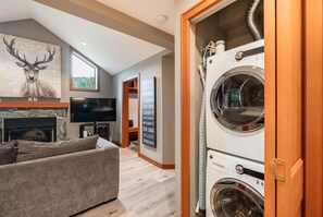 A modern living room with a fireplace, a large painting of a deer, a sofa, and a television. - Townhome | Complex hot tub | BBQ | Free Parking (Whistler)