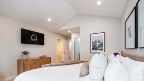 Una camera da letto con un letto, una cassettiera in legno, una televisione e quadri appesi al muro.