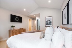 Ein Schlafzimmer mit einem Bett, einer Holzkommode, einem Fernseher und gerahmten Bildern an der Wand.