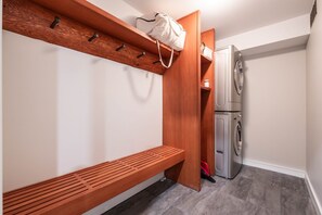 Ein Waschraum mit Waschmaschine, einer Bank und einem Holzboden mit Haken.