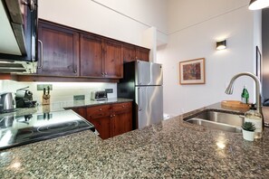 A kitchen with granite countertops, stainless steel appliances, wooden cabinets, a built-in oven, and a sink. - Townhome | Wifi | Complex hot tub | BBQ (Whistler)