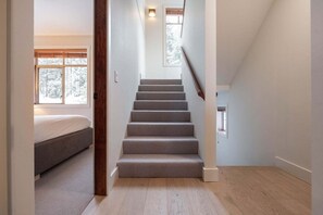 A staircase leading to a bedroom with a window, a door, and a small window on the landing. - Townhome | Wifi | Complex hot tub | BBQ (Whistler)