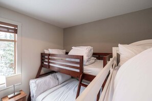 Ein Zimmer mit Etagenbetten, einem Fenster mit Jalousien und einem Nachttisch.