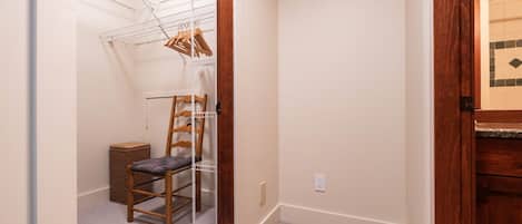 Un couloir étroit avec une chaise en bois, une étagère en métal et un petit panier en osier.