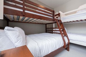 A bunk bed room with wooden railings and white bedding. - Townhome | Wifi | Complex hot tub | BBQ (Whistler)