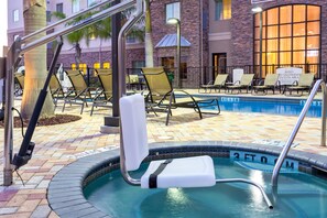 A pool area with lounge chairs and a hot tub.