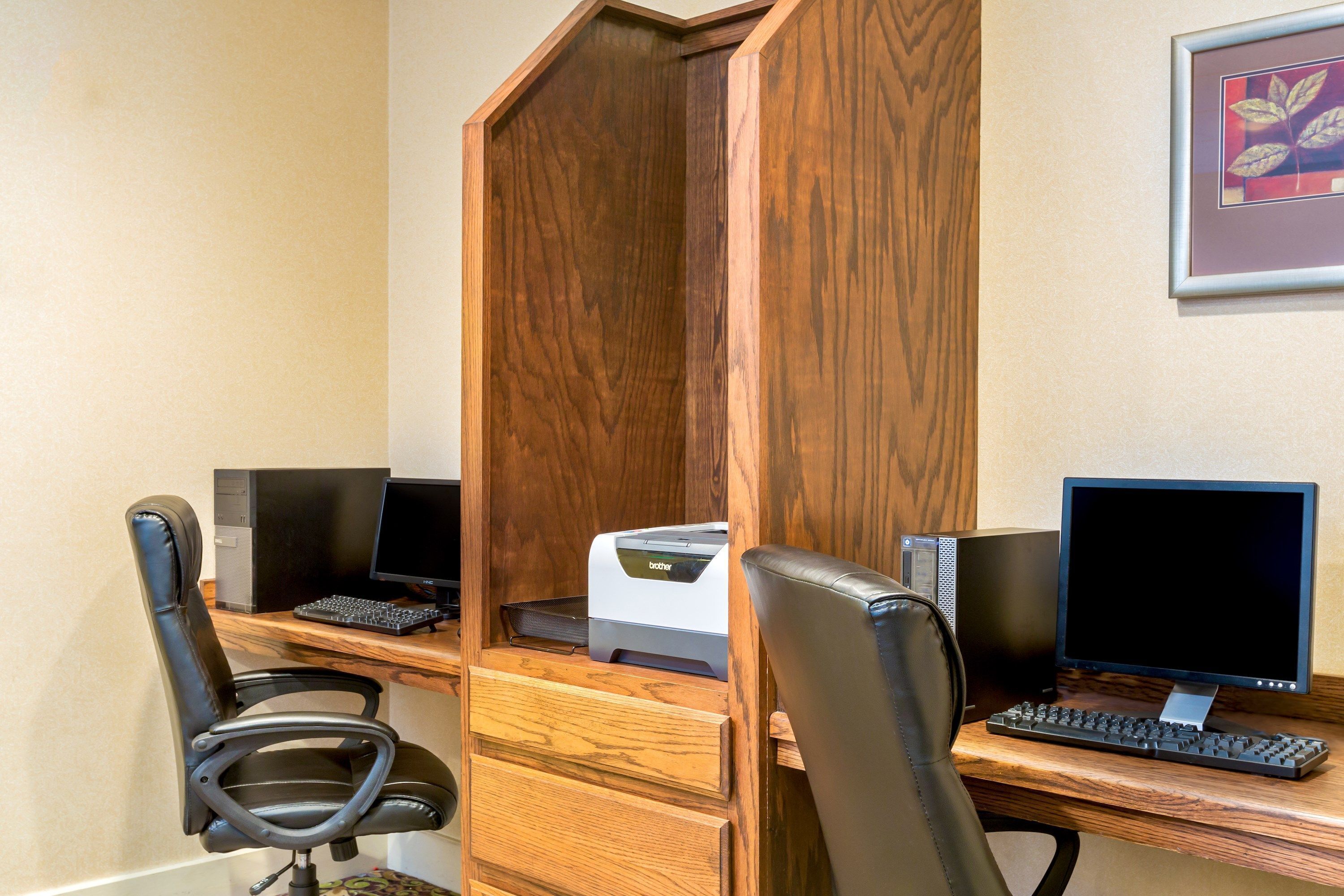 A workspace with two computer desks, one with a printer, and two office chairs.