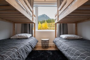 A room with two bunk beds, a small round table, and a view of mountains through a window. - Gorgeous Chalet | Private hot tub | BBQ | WIFI (Whistler)