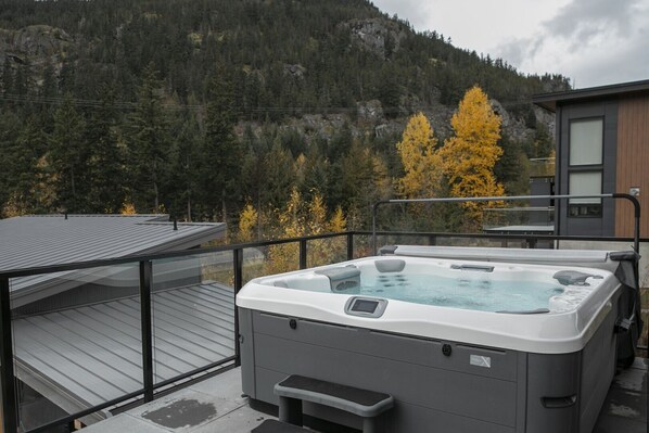 A hot tub on a deck with a mountain backdrop. - Gorgeous Chalet | Private hot tub | BBQ | WIFI (Whistler)