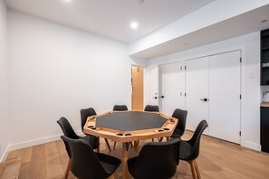 A conference room with a round table, black chairs, white walls, and wooden flooring. - Gorgeous Chalet | Private hot tub | BBQ | WIFI (Whistler)