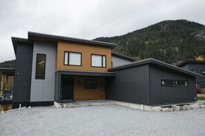 A modern two-story house with a garage, a front porch, and a driveway. - Gorgeous Chalet | Private hot tub | BBQ | WIFI (Whistler)