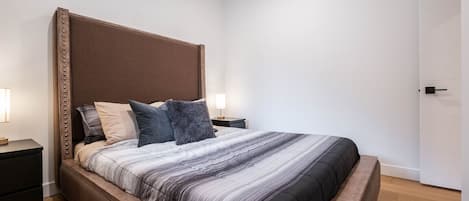 A modern bedroom with a large bed, two bedside tables, and a nightstand.