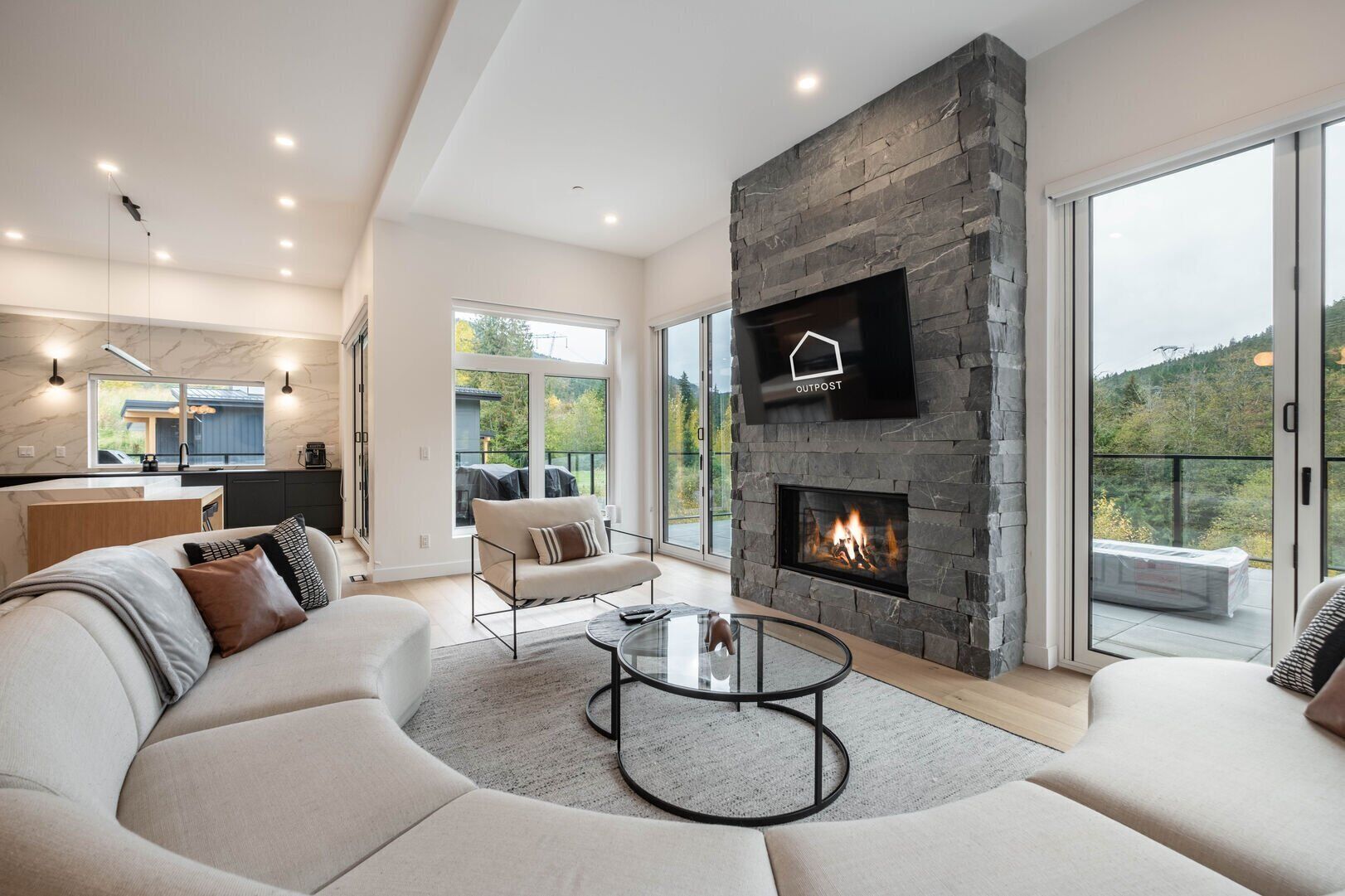 A modern living room with a stone fireplace, a sofa, and a glass coffee table.