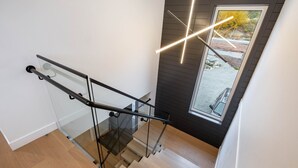 Een moderne trap met glazen balustrades en een eigentijdse lamp.