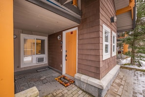 Ein Haus mit Holzwand, einer Haustür und einem Fenster mit Rollläden.