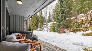 A cozy outdoor seating area with a hot tub, wooden furniture, and a snow-covered landscape with trees. - Free Parking | Private hot tub | Blueberry Hill (Whistler)